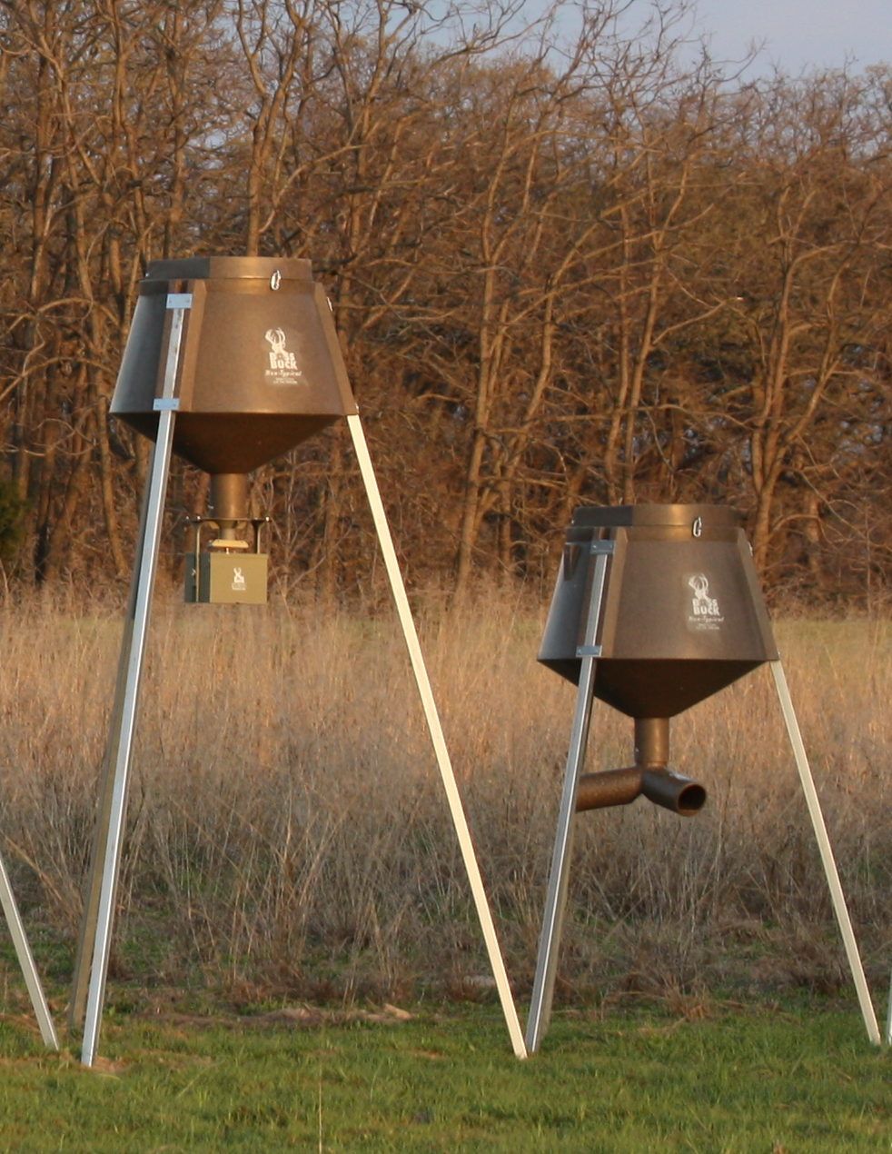 two deer feeders are sitting in a field with trees in the background