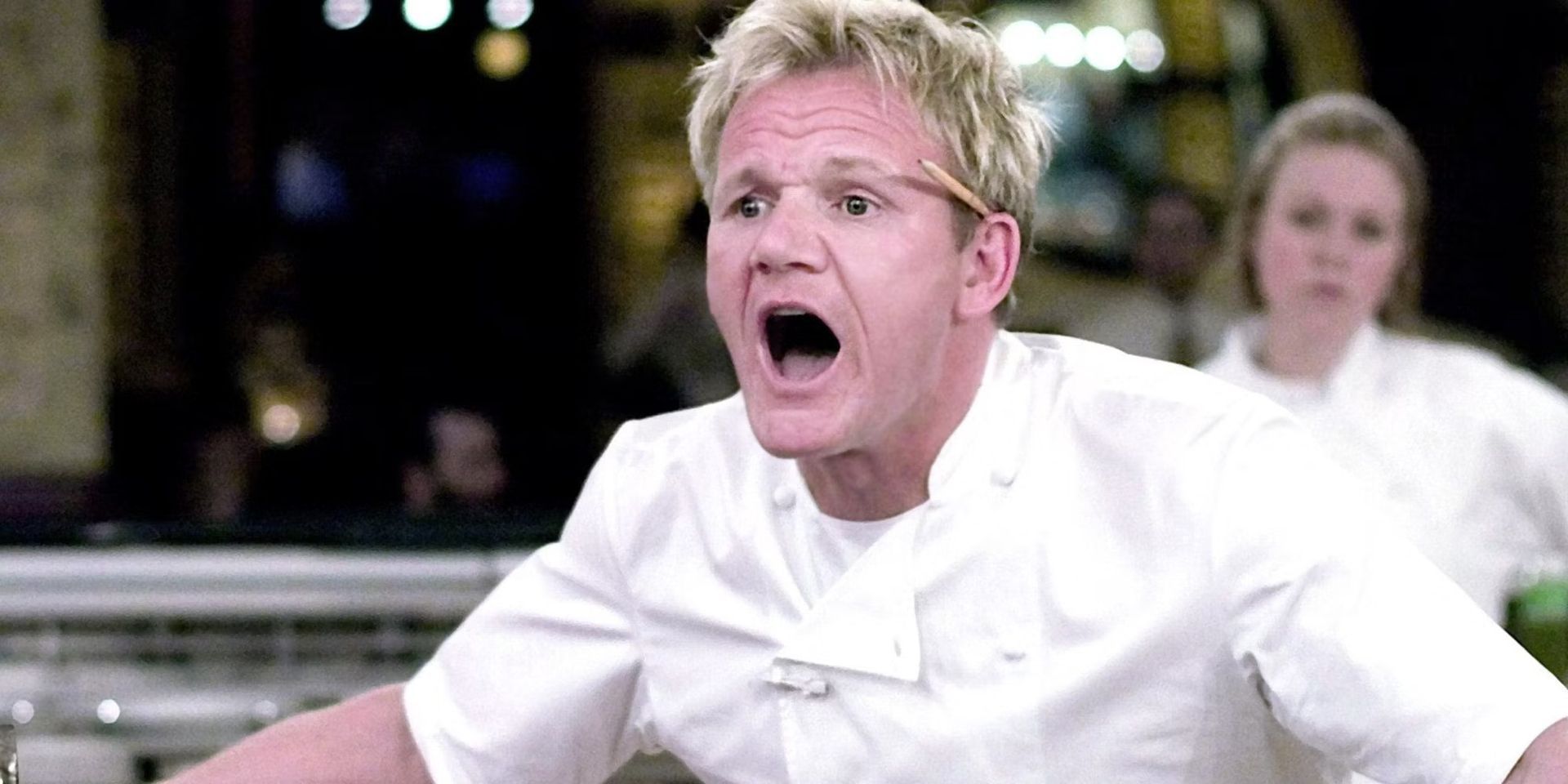 A man in a chef 's uniform is making a funny face with his mouth open.