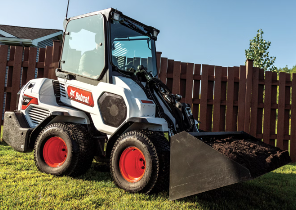 a bobcat tractor is parked in front of a wooden fence