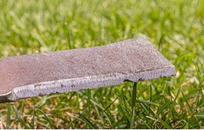 a piece of concrete is sitting on top of a lush green field .