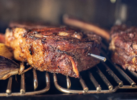 A steak is cooking on a grill with a toothpick sticking out of it.