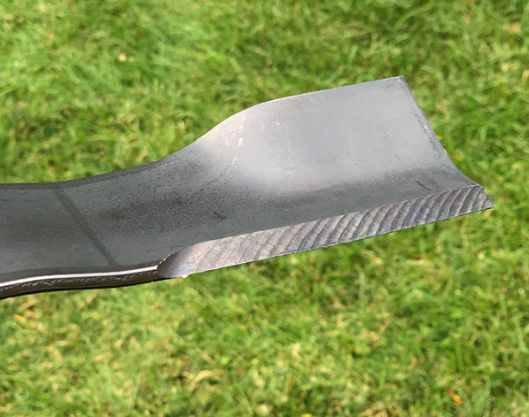 A close up of a lawn mower blade on a lawn.