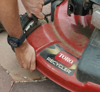 A person is working on a toro recycling lawn mower