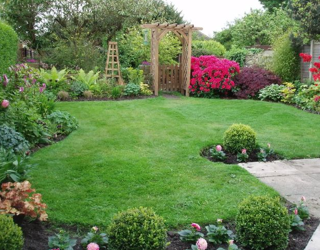 A lush green garden with a pergola and flowers