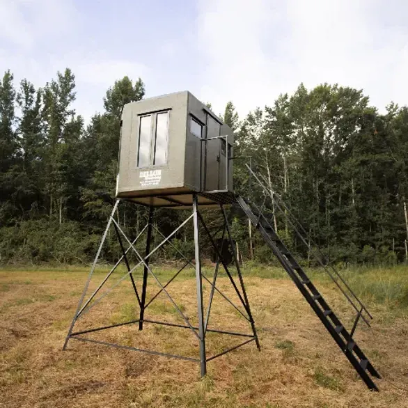 a deer stand with stairs is sitting in the middle of a field .