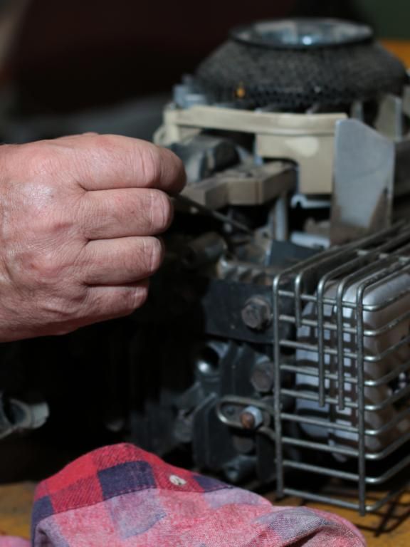 A person is working on a two stroke engine with a screwdriver