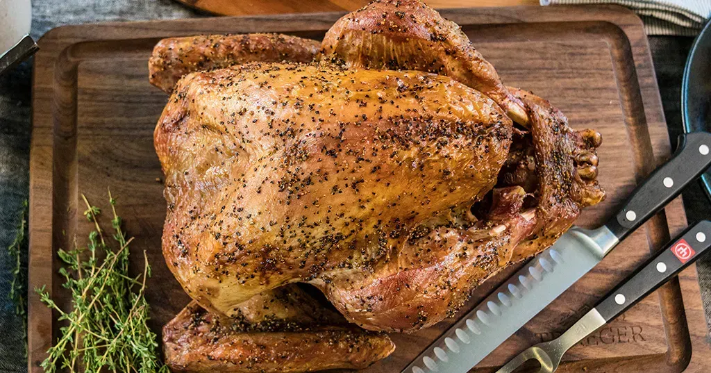 A turkey on a wooden board with a knife next to it 