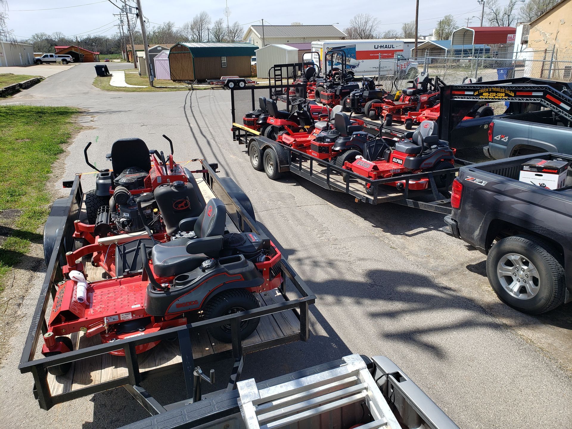 several lawn mower trailers are parked in front of a u-haul truck