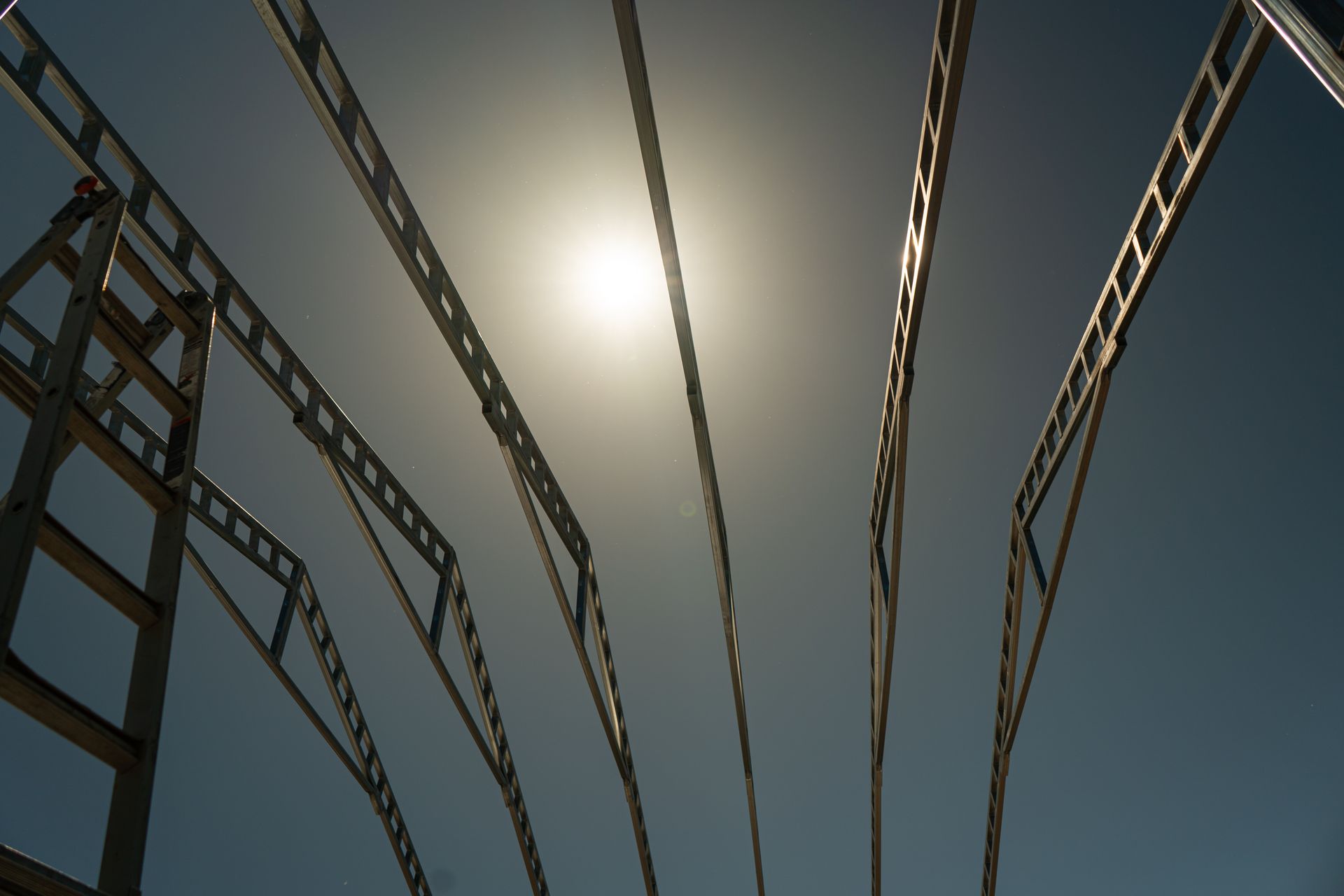 Looking up at a metal building frame with the sun shining through it