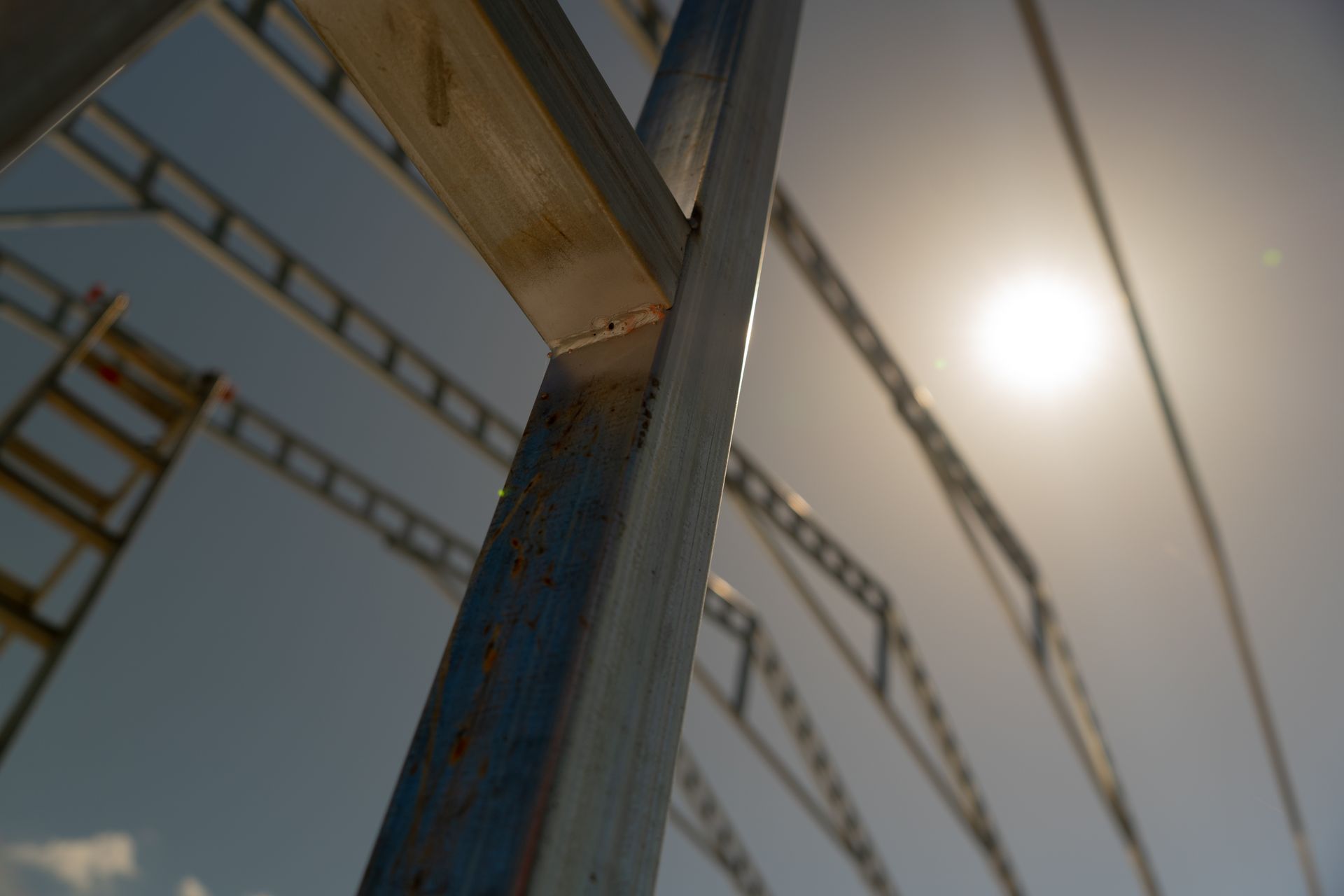 Looking up at a metal structure with the sun shining through it