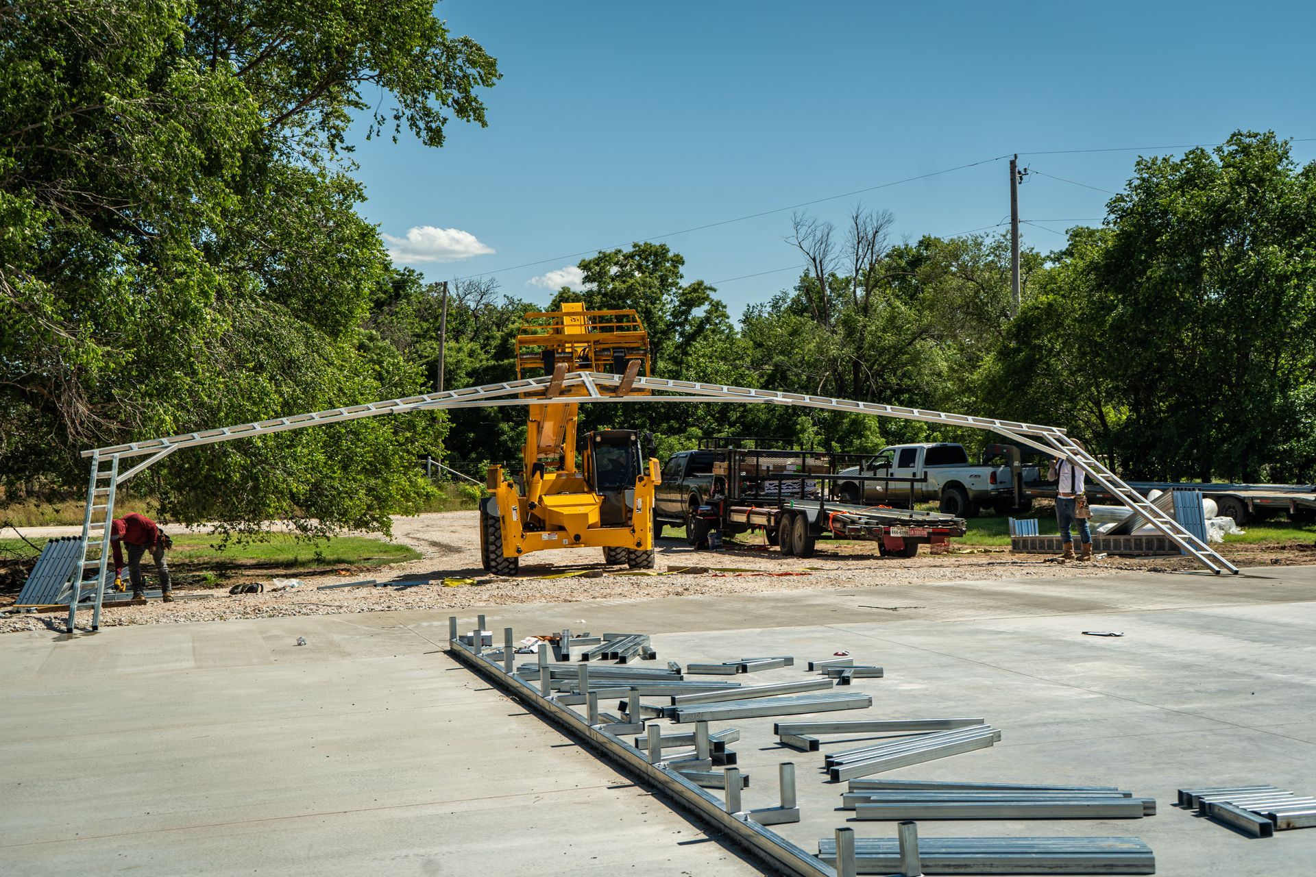 A yellow forklift is carrying a metal structure on a concrete surface.