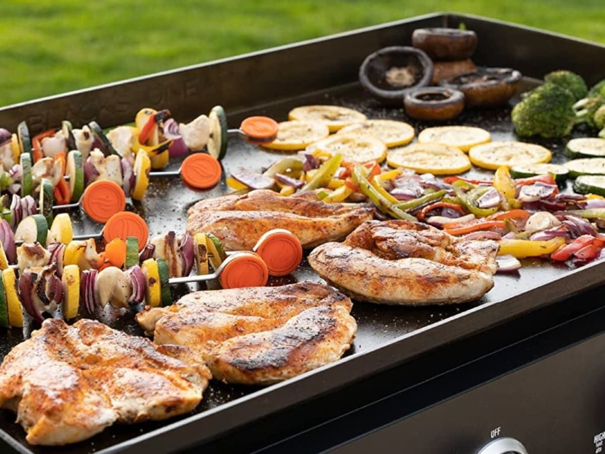 Chicken and vegetables are being cooked on a Blackstone grill.