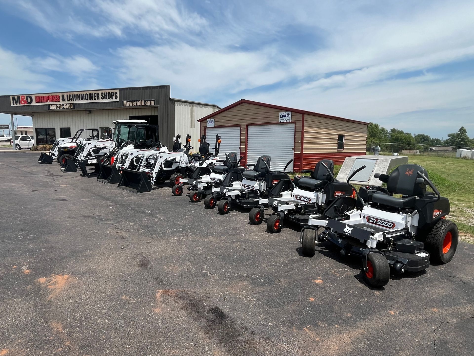 A row of lawn mowers are parked in front of a building.