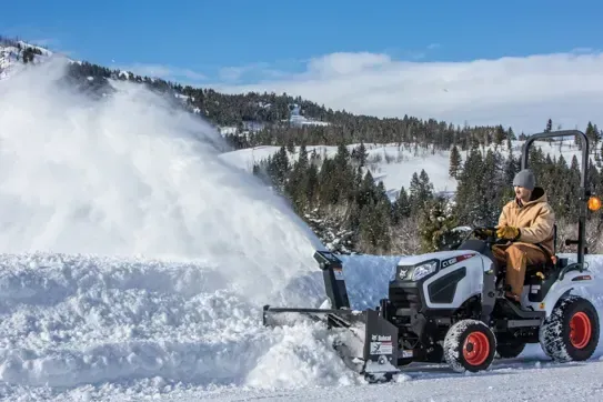 a man is driving a bobcat tractor in a park