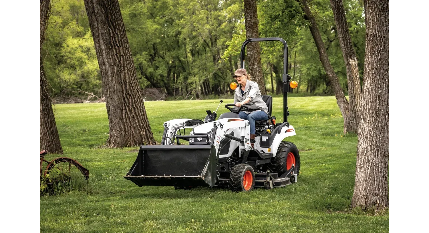 Una mujer monta un tractor en un campo de hierba.