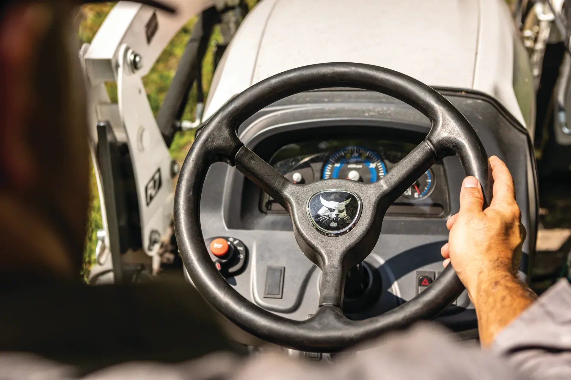 A man is driving a bobcat tractor with a steering wheel.