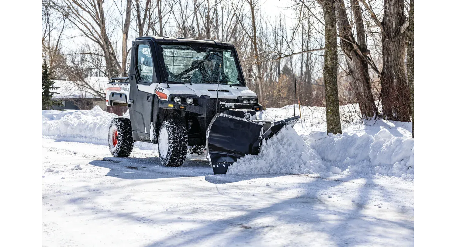 A utility vehicle is plowing snow on a snowy road.