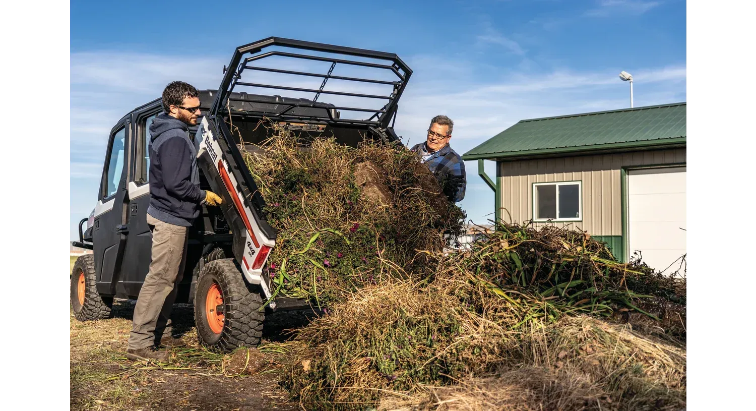 a man is unloading a pile of grass from a utility vehicle