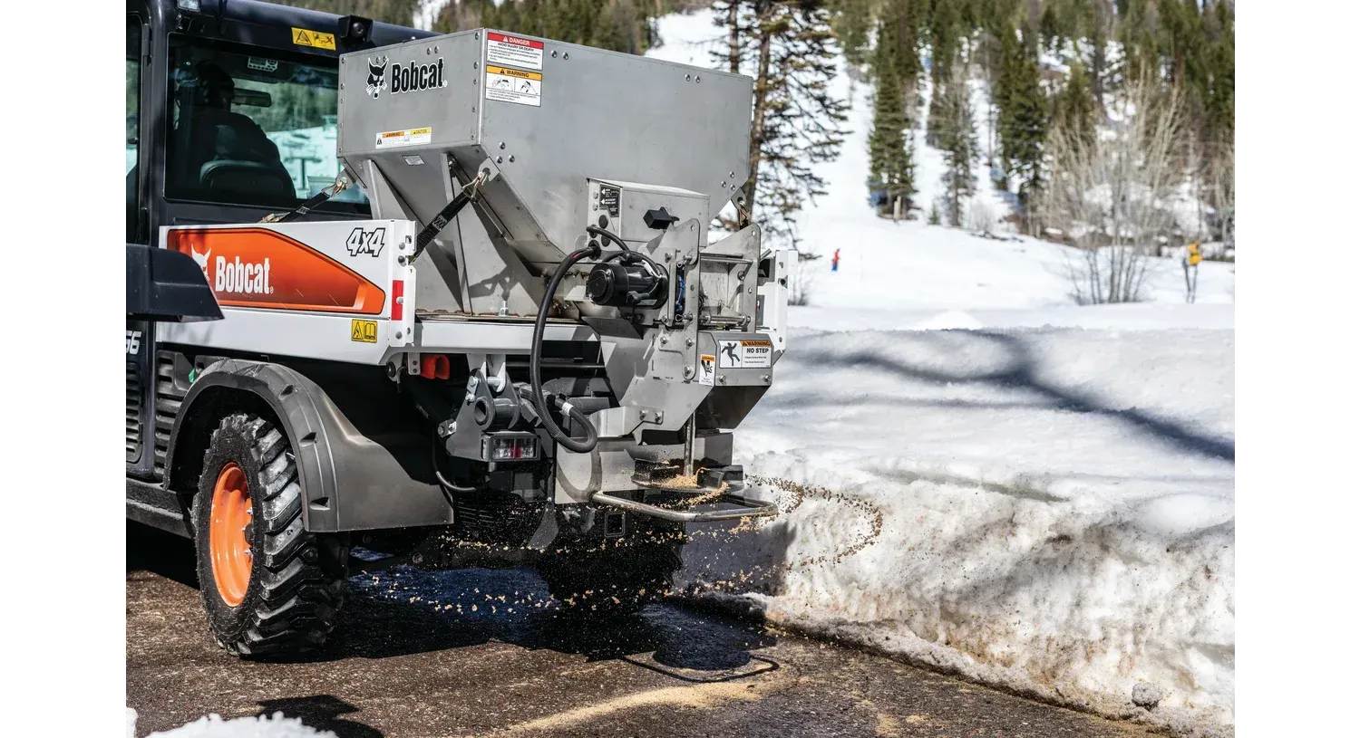 A tractor is spreading salt on a snowy road.