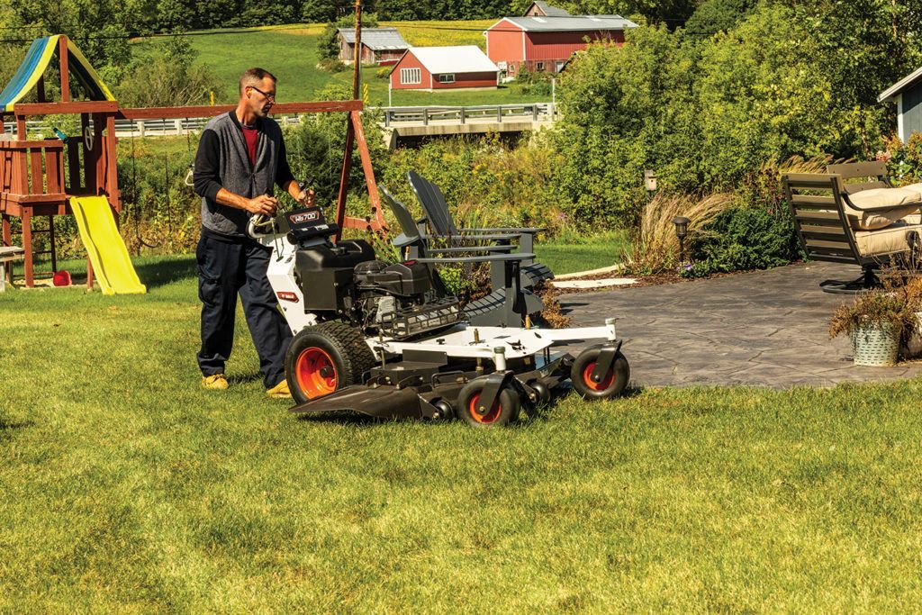 a man is driving a bobcat tractor in a park
