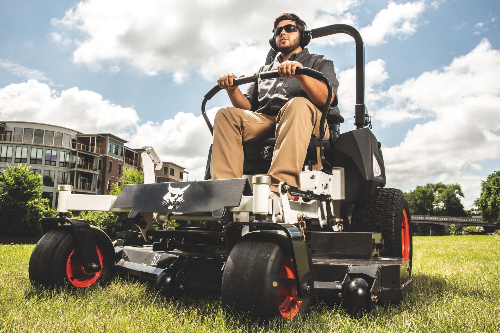 a man is sitting on a bobcat lawn mower in a grassy field .