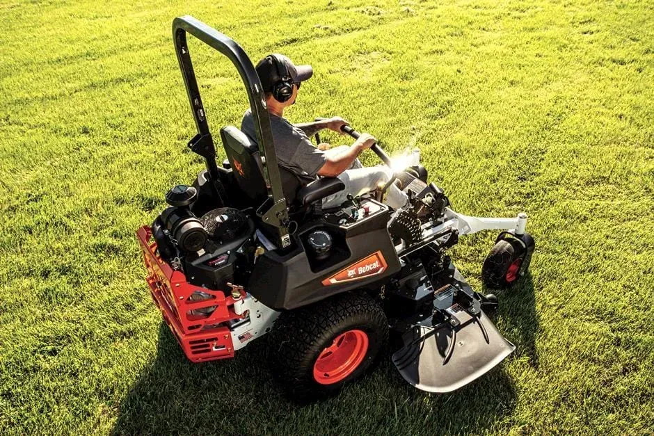 A man is riding a lawn mower on a lush green field.