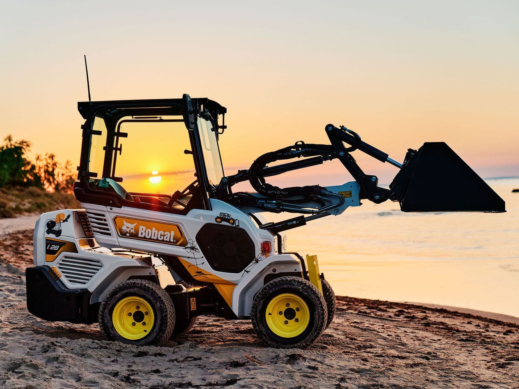 a bobcat loader is parked on the beach at sunset