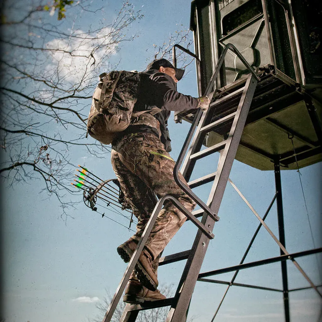 A man with a backpack is climbing a ladder to a tower.