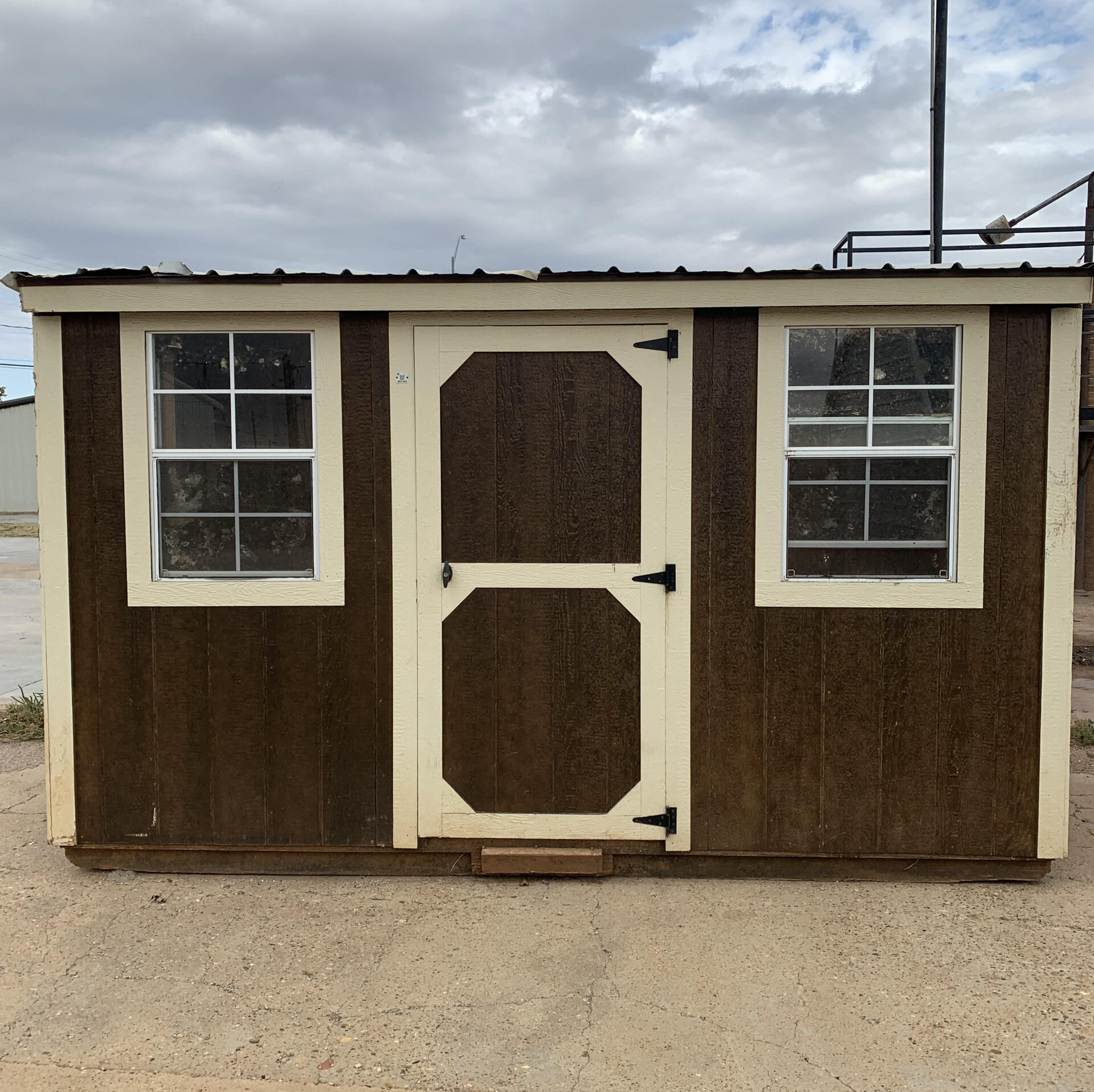 Un cobertizo marrón y blanco con dos ventanas y una puerta