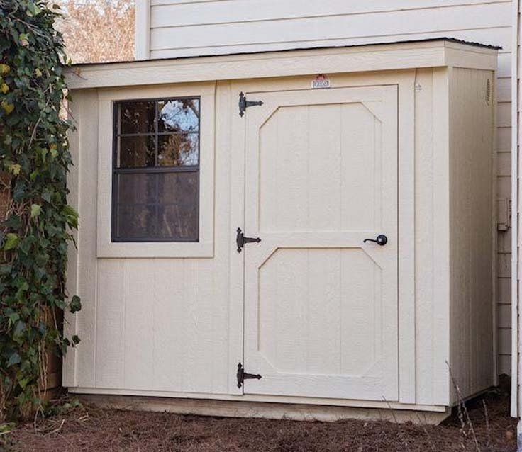 A white shed with a window on the side of a house