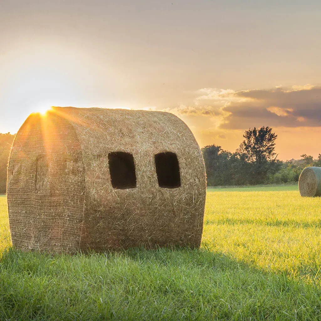 redneck bale blind  in a field with the sun shining through the clouds