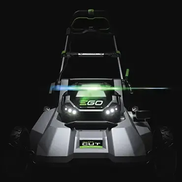 the front of a ego lawn mower is lit up in the dark .