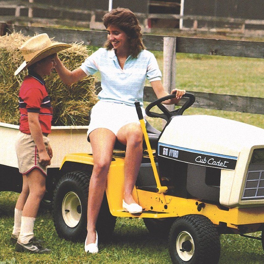 a woman is sitting on a cub cadet lawn mower