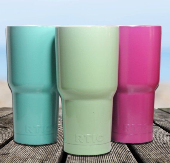 Three different colored tumblers are sitting on a wooden table.