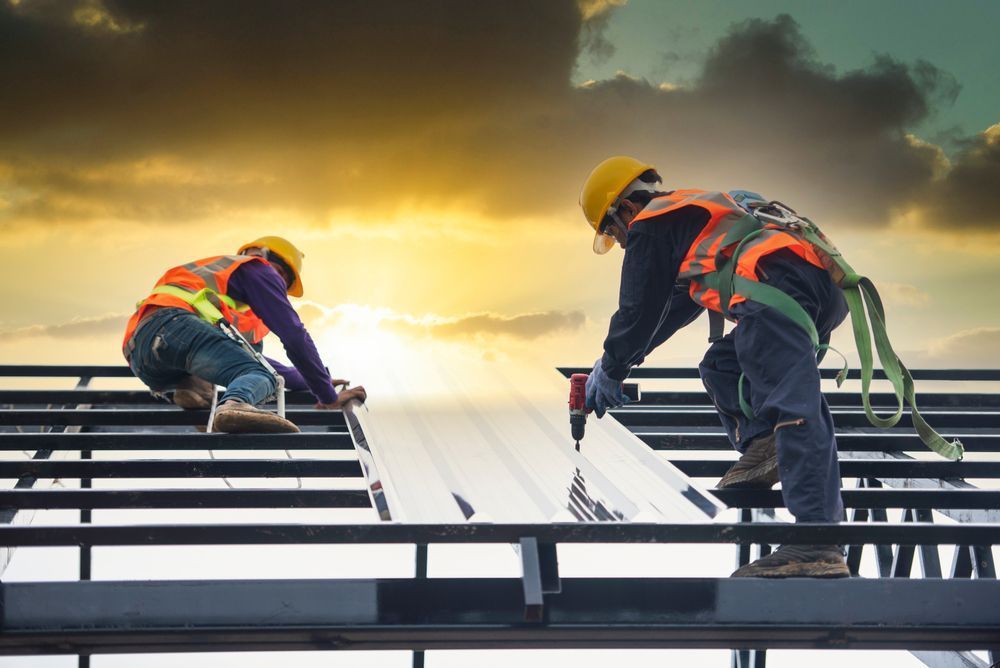 two workers on a roof installing standing seam metal