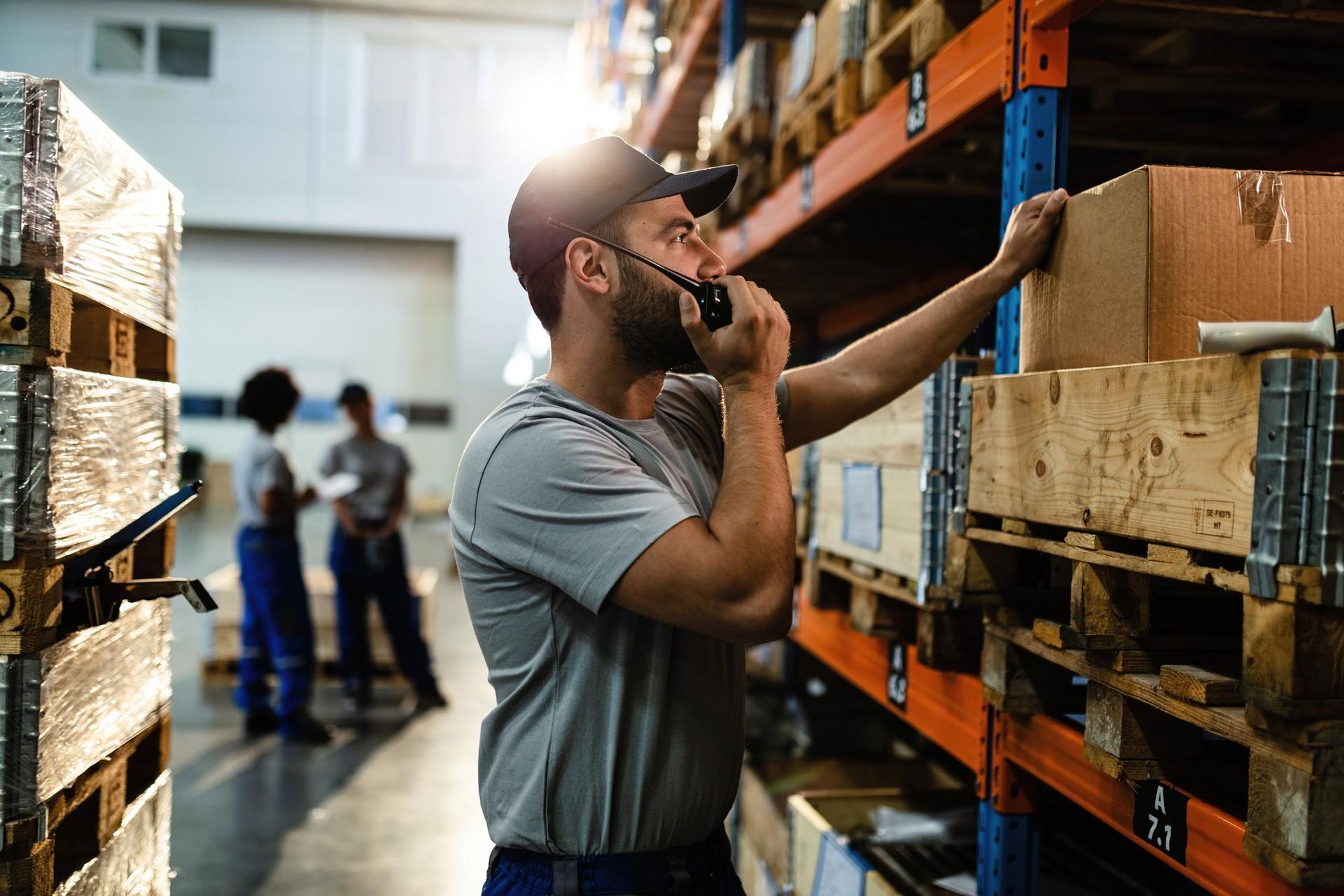 A man is talking on a walkie talkie in a warehouse.