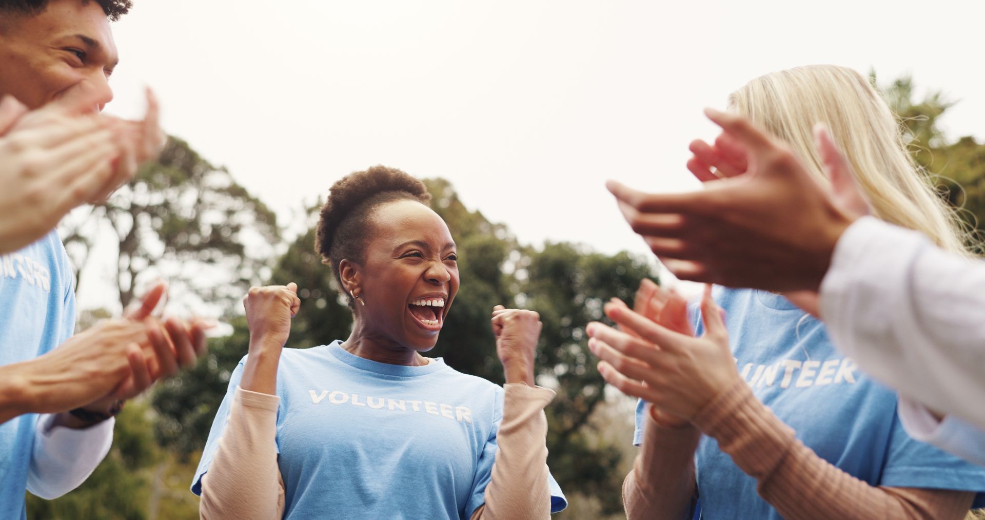 A group of volunteers are clapping their hands in a park.
