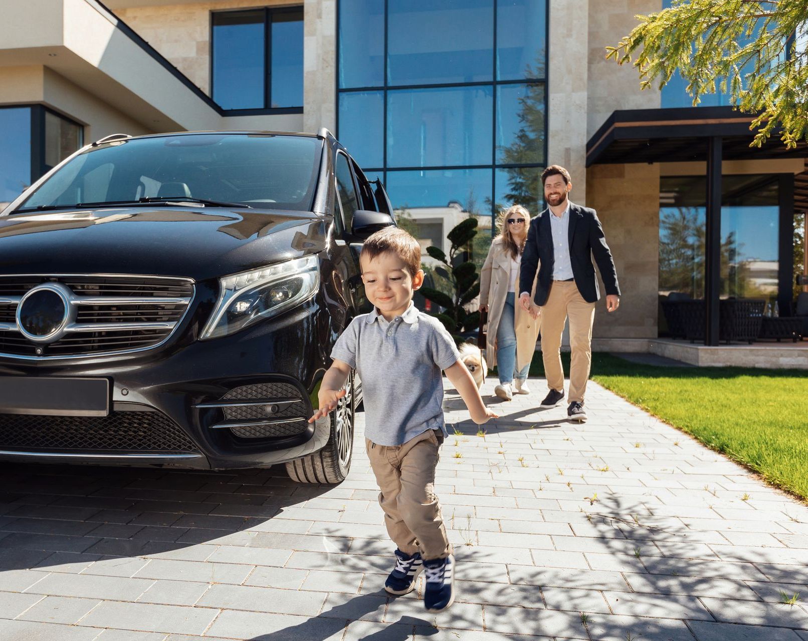 A family is walking towards a car parked in front of a house.