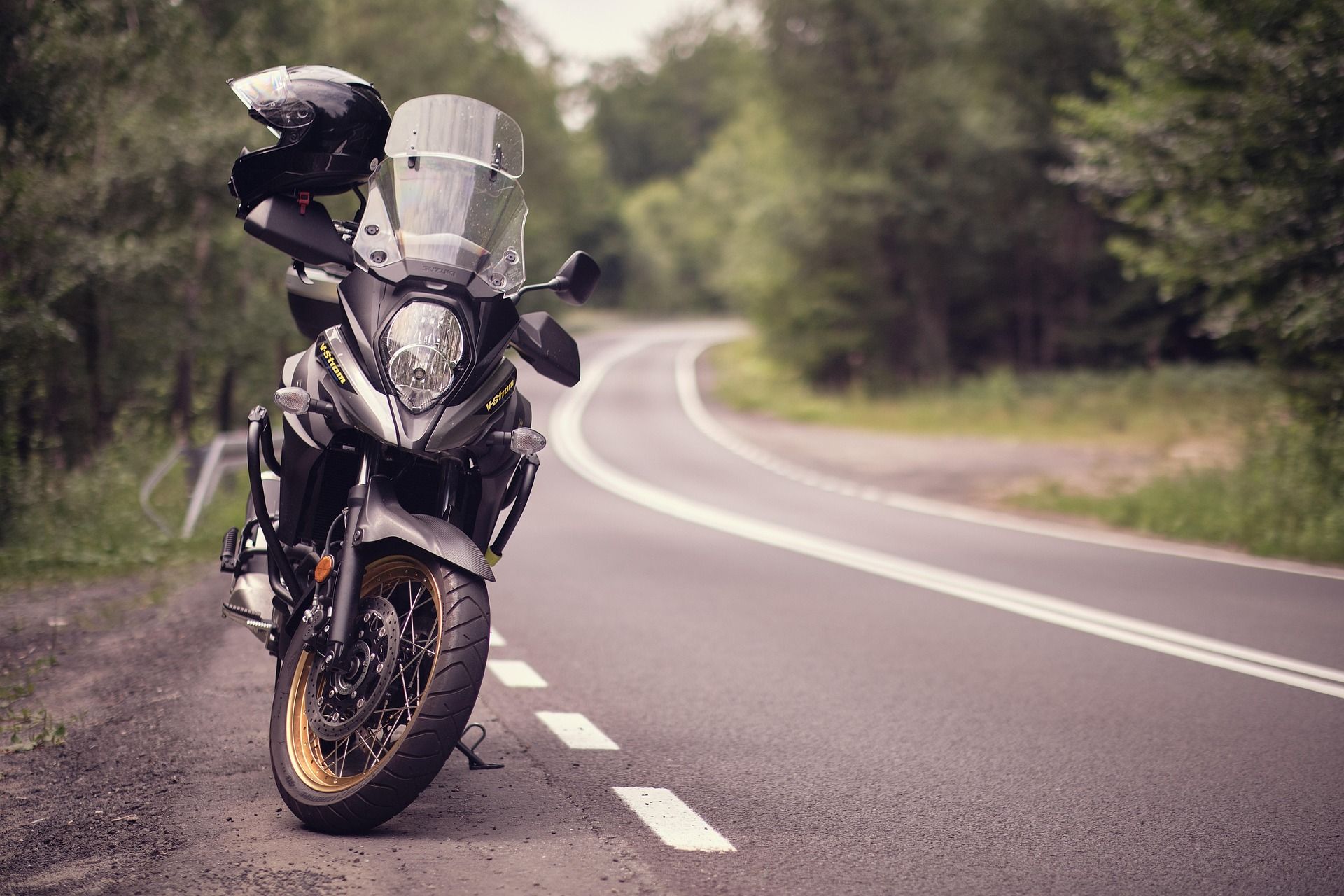 A motorcycle is parked on the side of a curvy road.