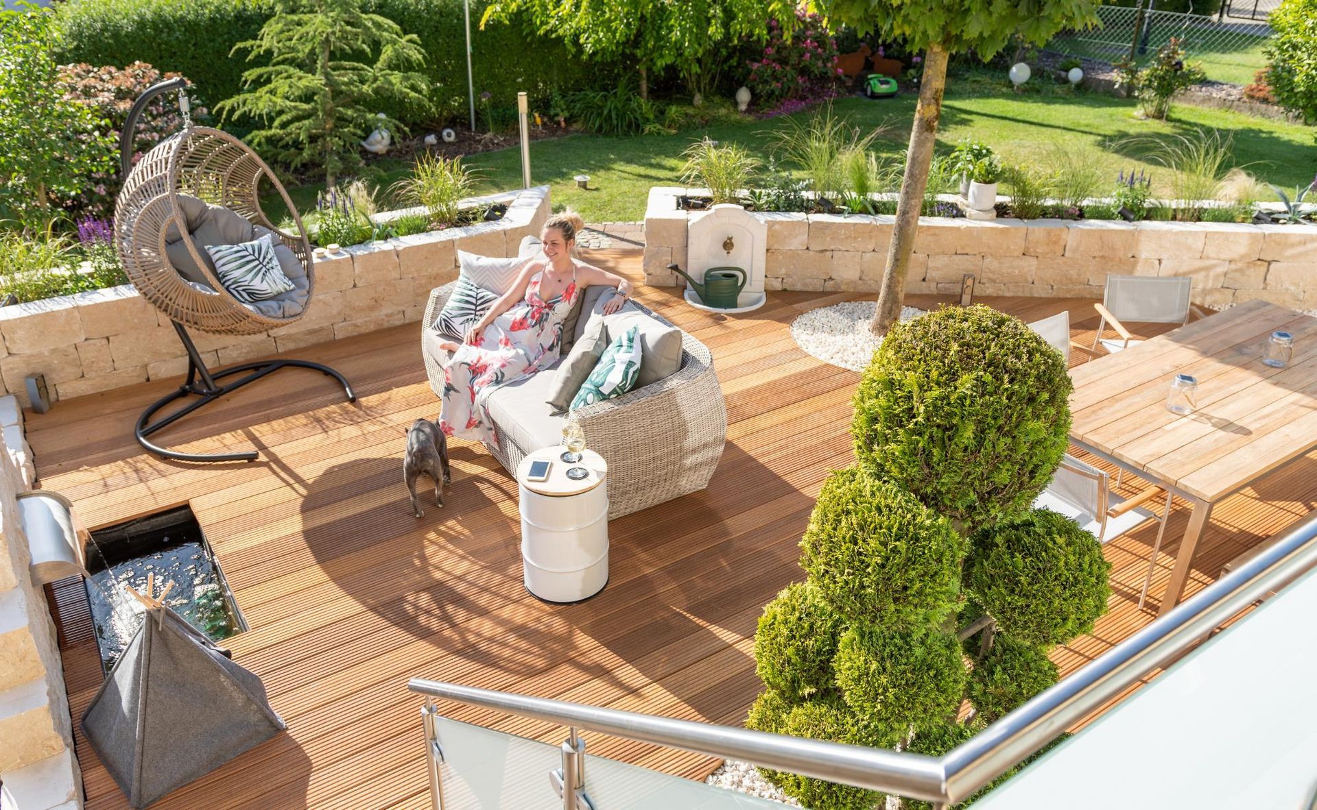Woman relaxing on outdoor patio with wood deck and hanging chair.