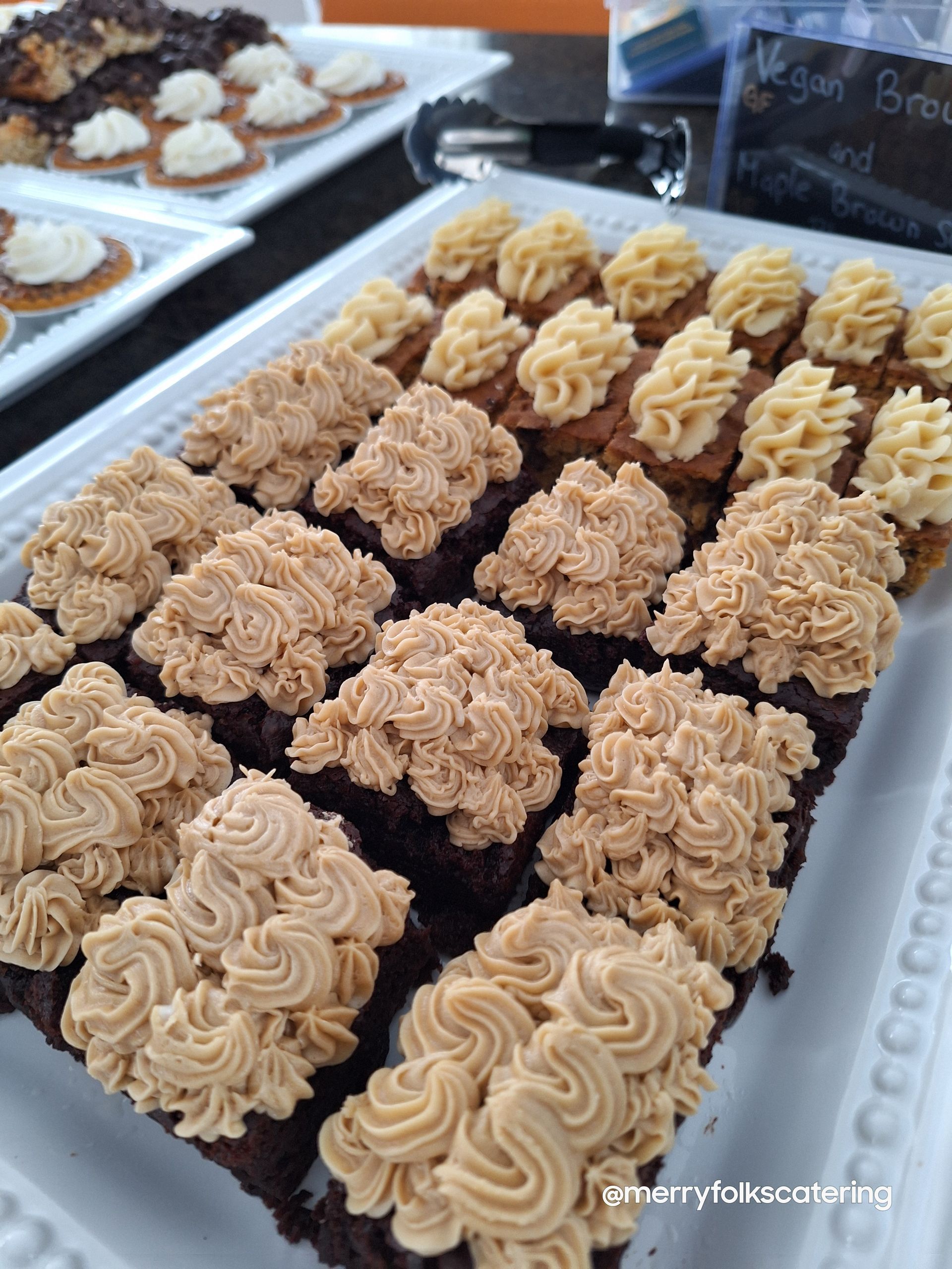 Brownies with beige frosting, displayed on a white platter.