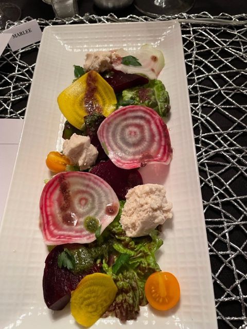 Beet salad on rectangular white plate: colorful beets, goat cheese, greens, and balsamic glaze.