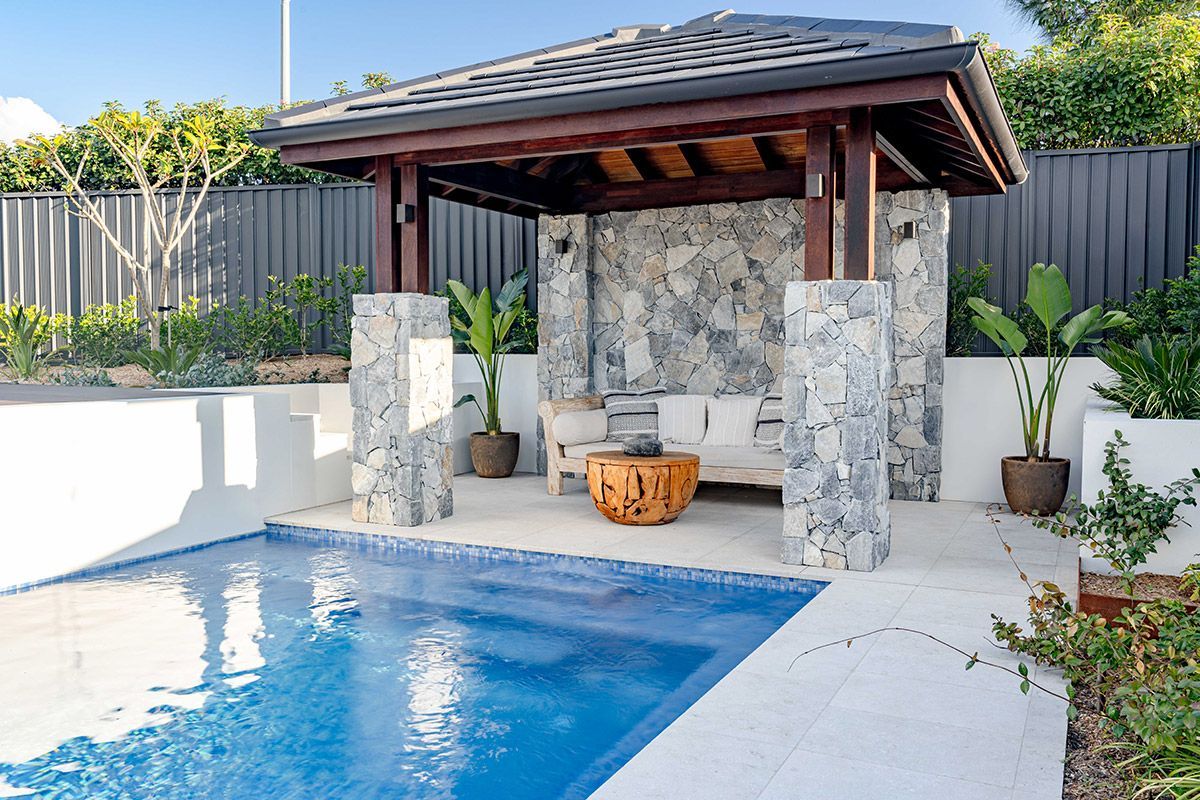 Outdoor night scene with illuminated pool, stone steps, and walkway.