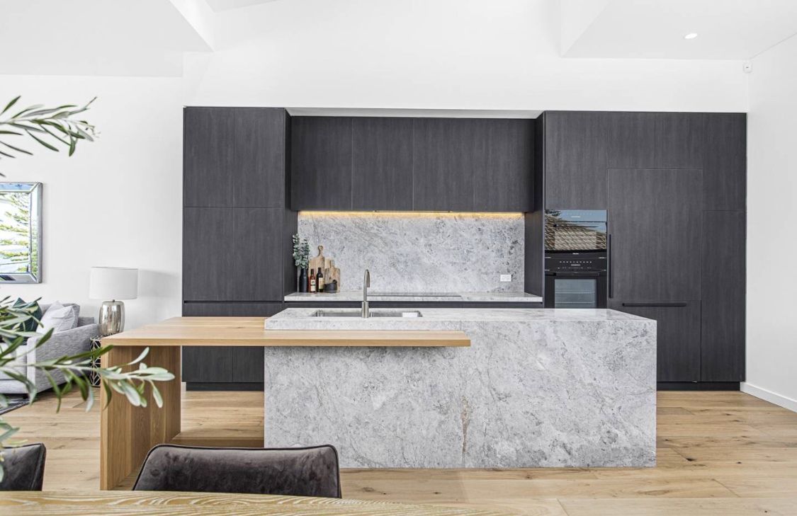 Modern kitchen with grey cabinetry, marble island, and wooden table extension — LG Constructions in Thirroul, NSW