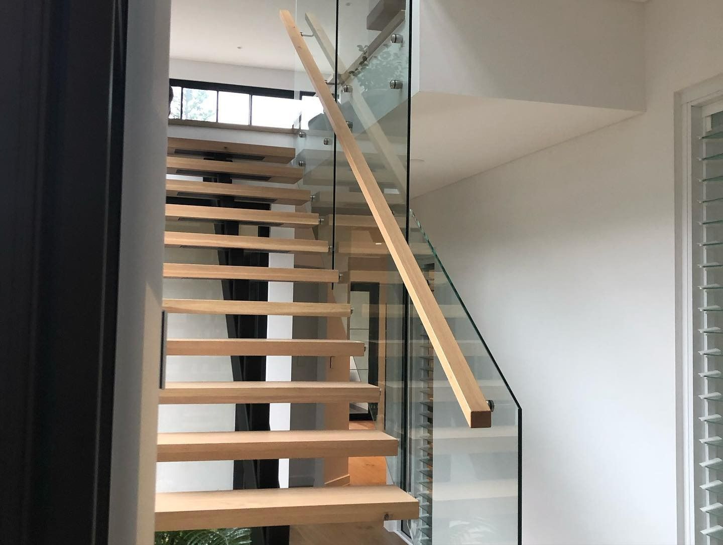 A Wooden Staircase With a Glass Railing in a House — LG Constructions in Thirroul, NSW