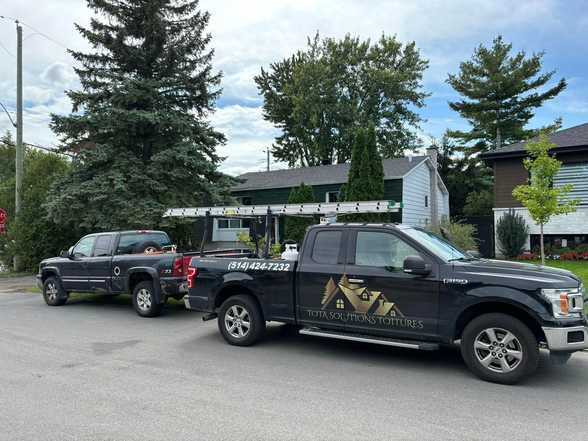 Deux camions sont garés sur le bord de la route devant une maison.