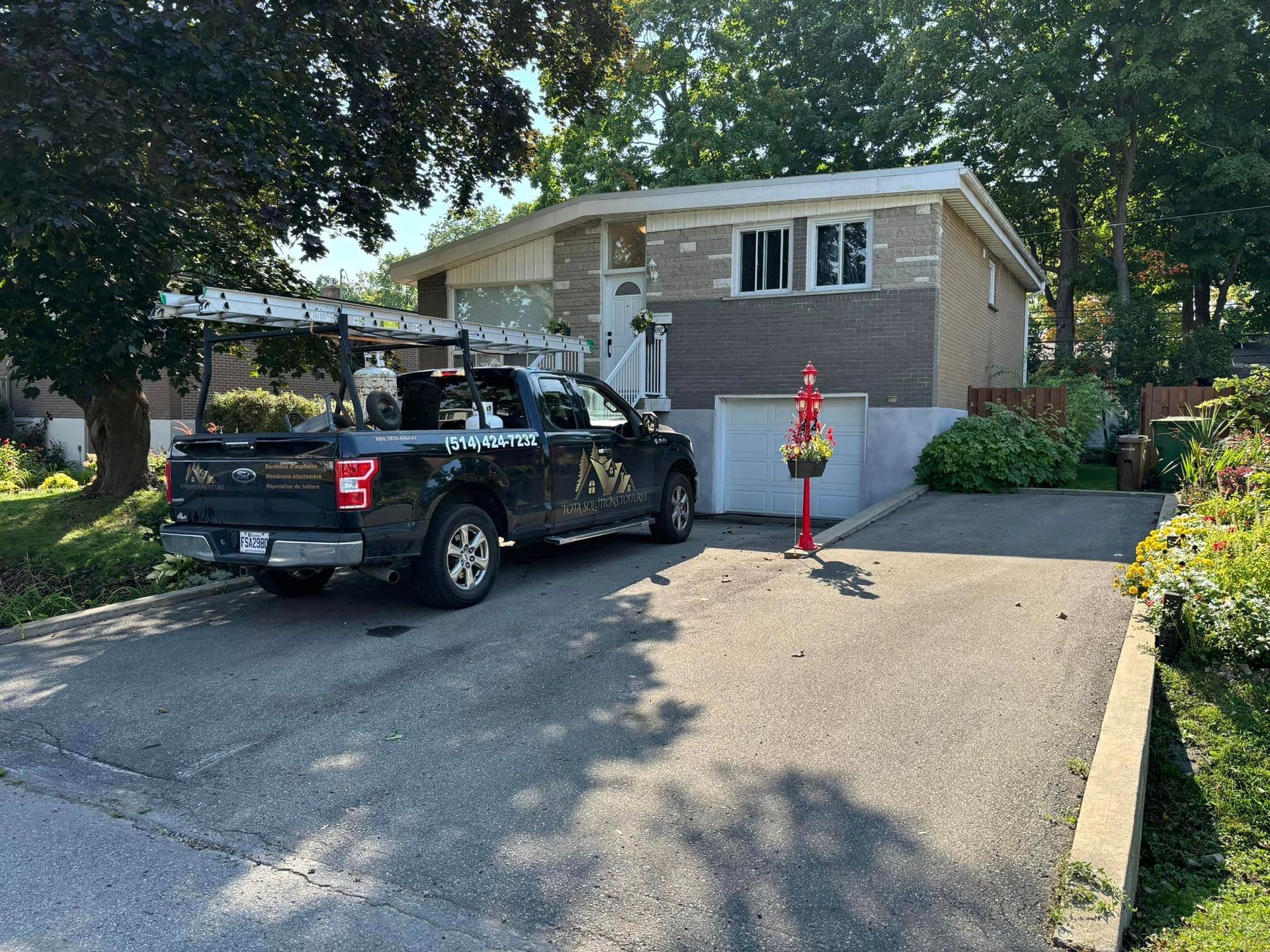 Un camion noir est garé devant une maison.