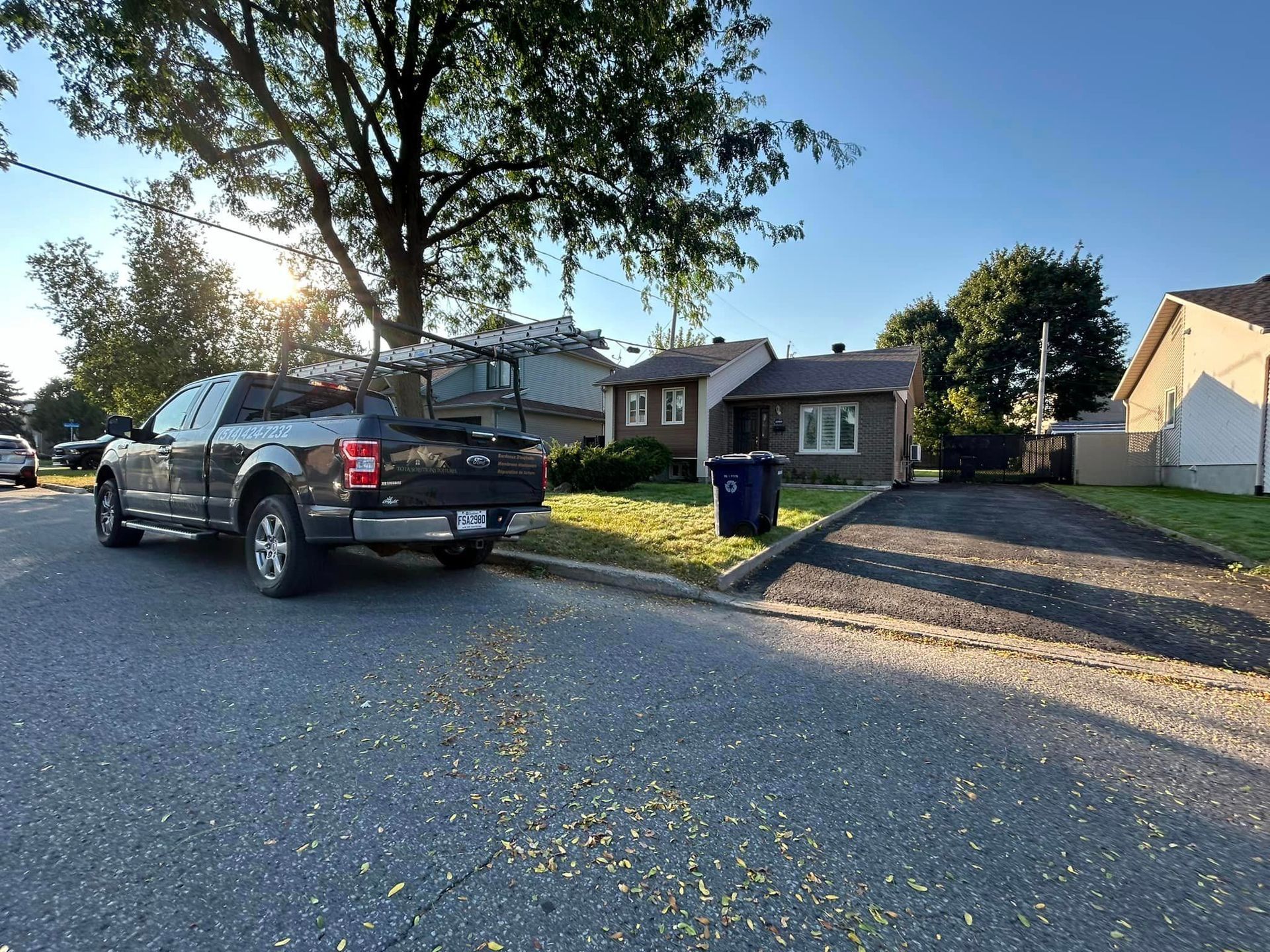 Un camion noir est garé sur le bord de la route devant une maison.