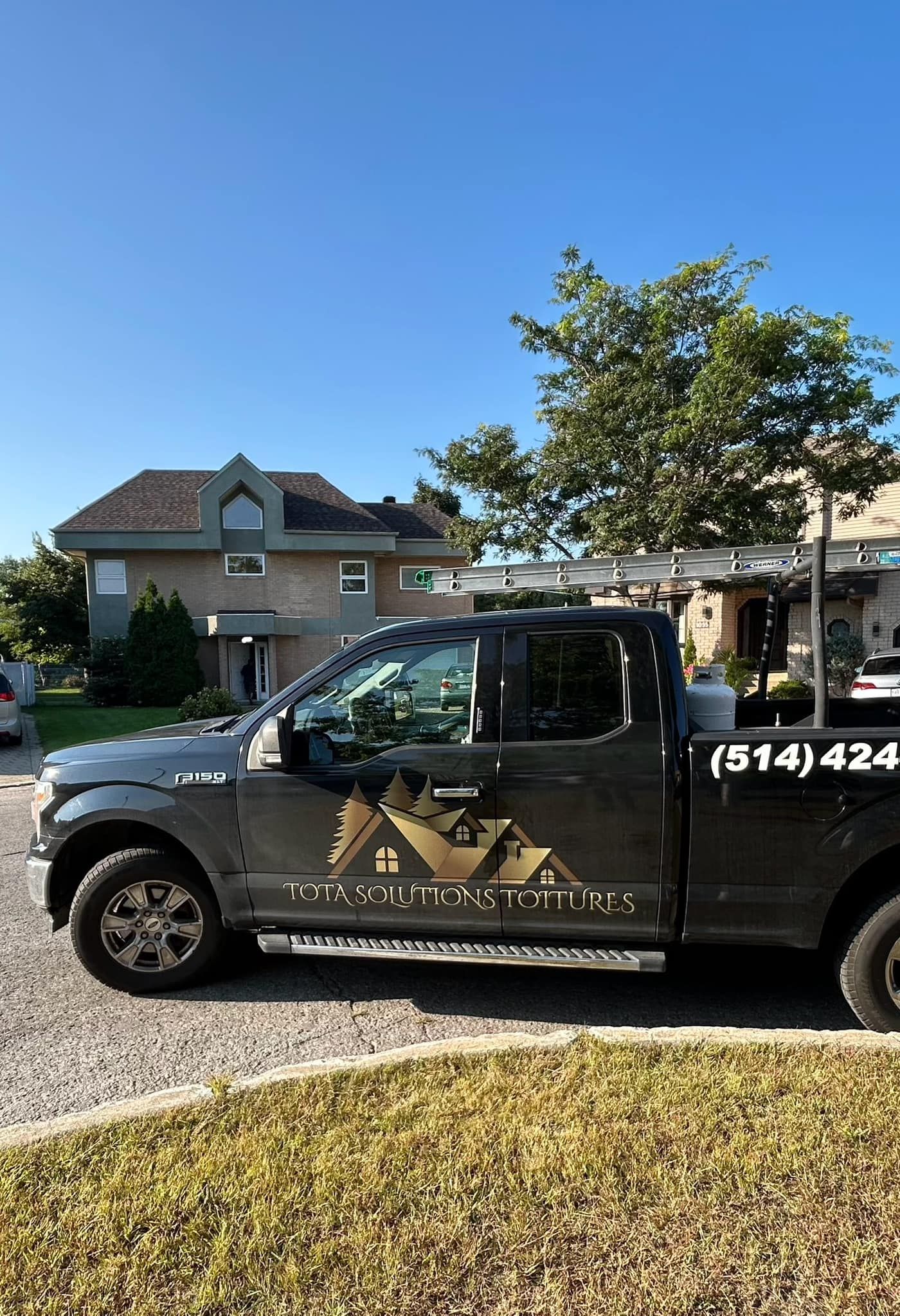 Un camion noir est garé devant une maison.