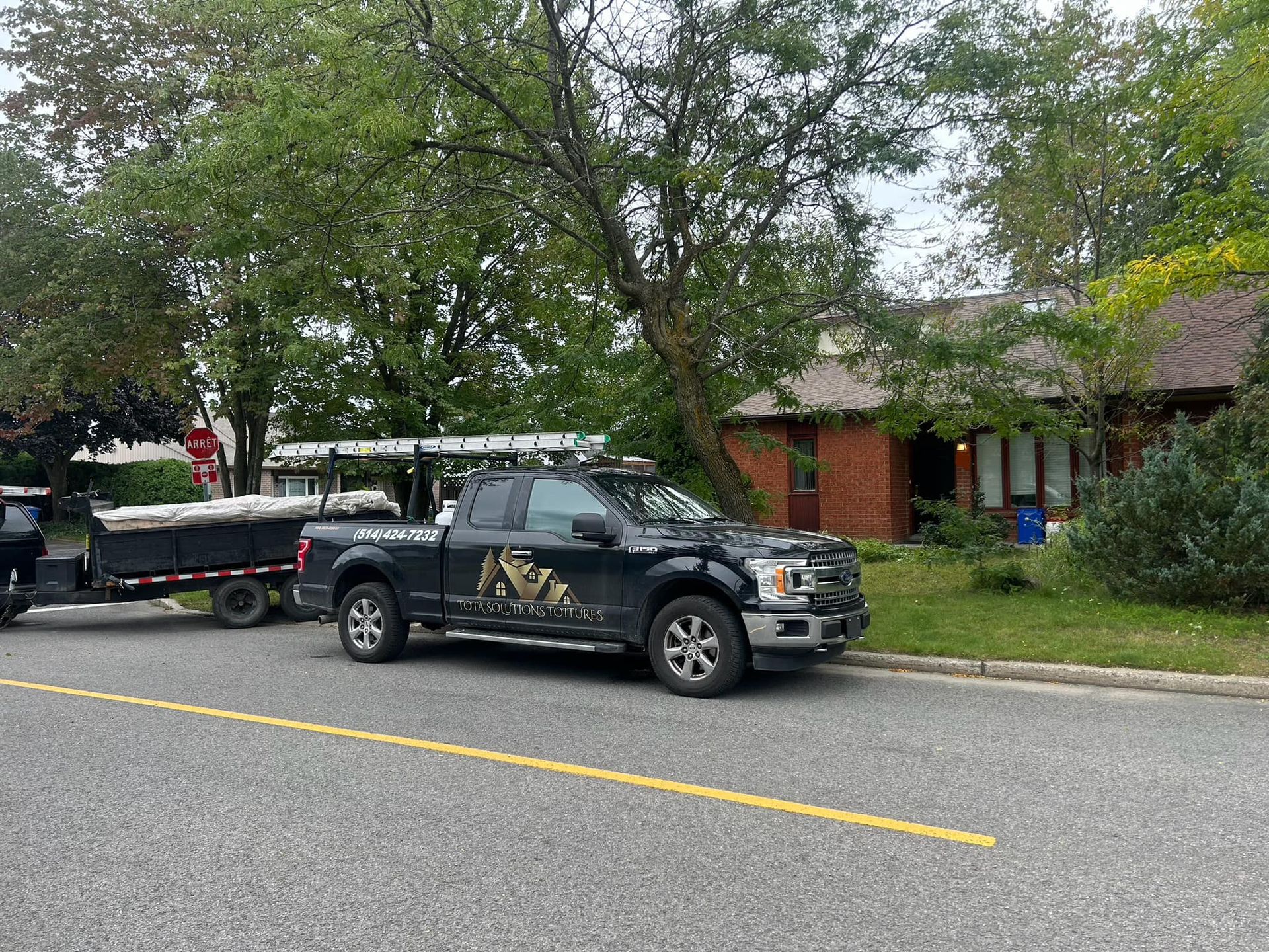 Un camion noir est garé sur le bord de la route à côté d'une maison.